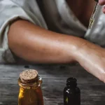 A woman applies oils to her hand with a pipette