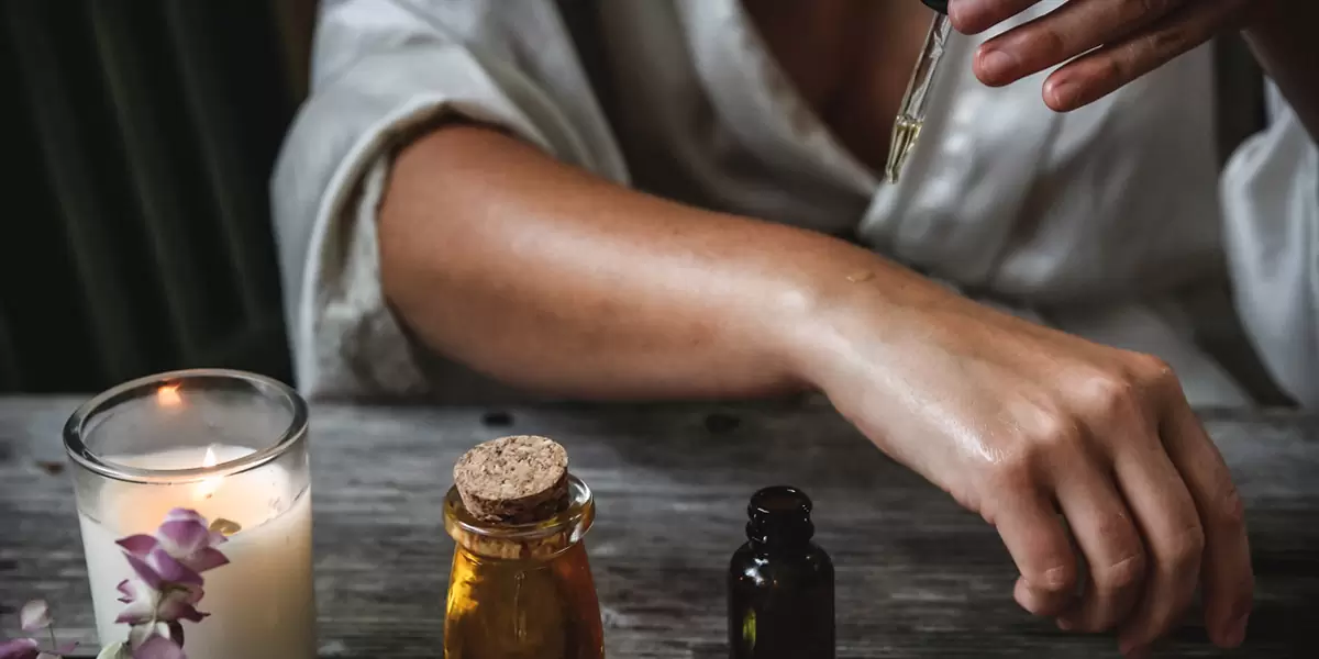 A woman applies oils to her hand with a pipette
